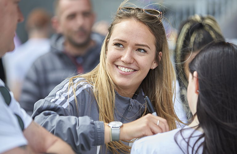 A member of Sheffield United's women's team signs autographs at the Rainbow Laces charity football match